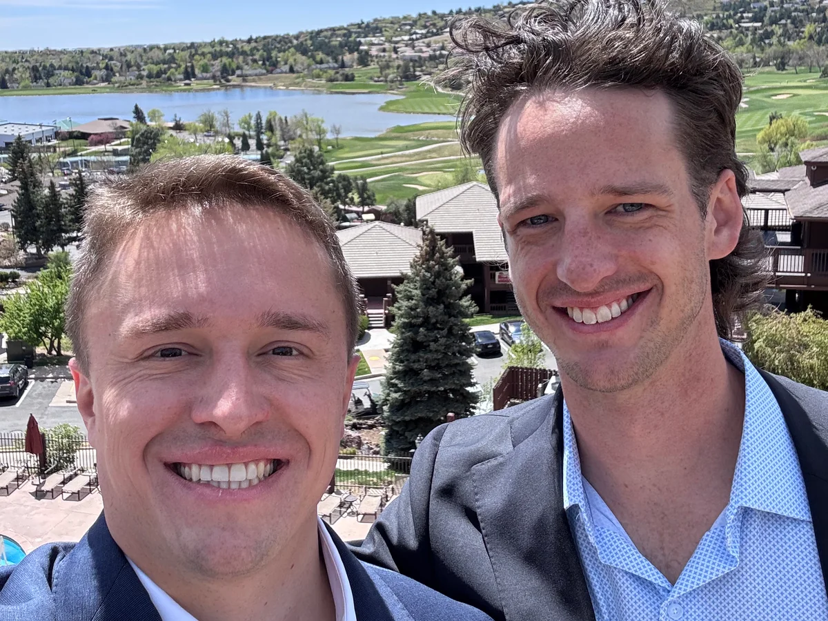 Two teammates outdoors with a lake and hills behind them