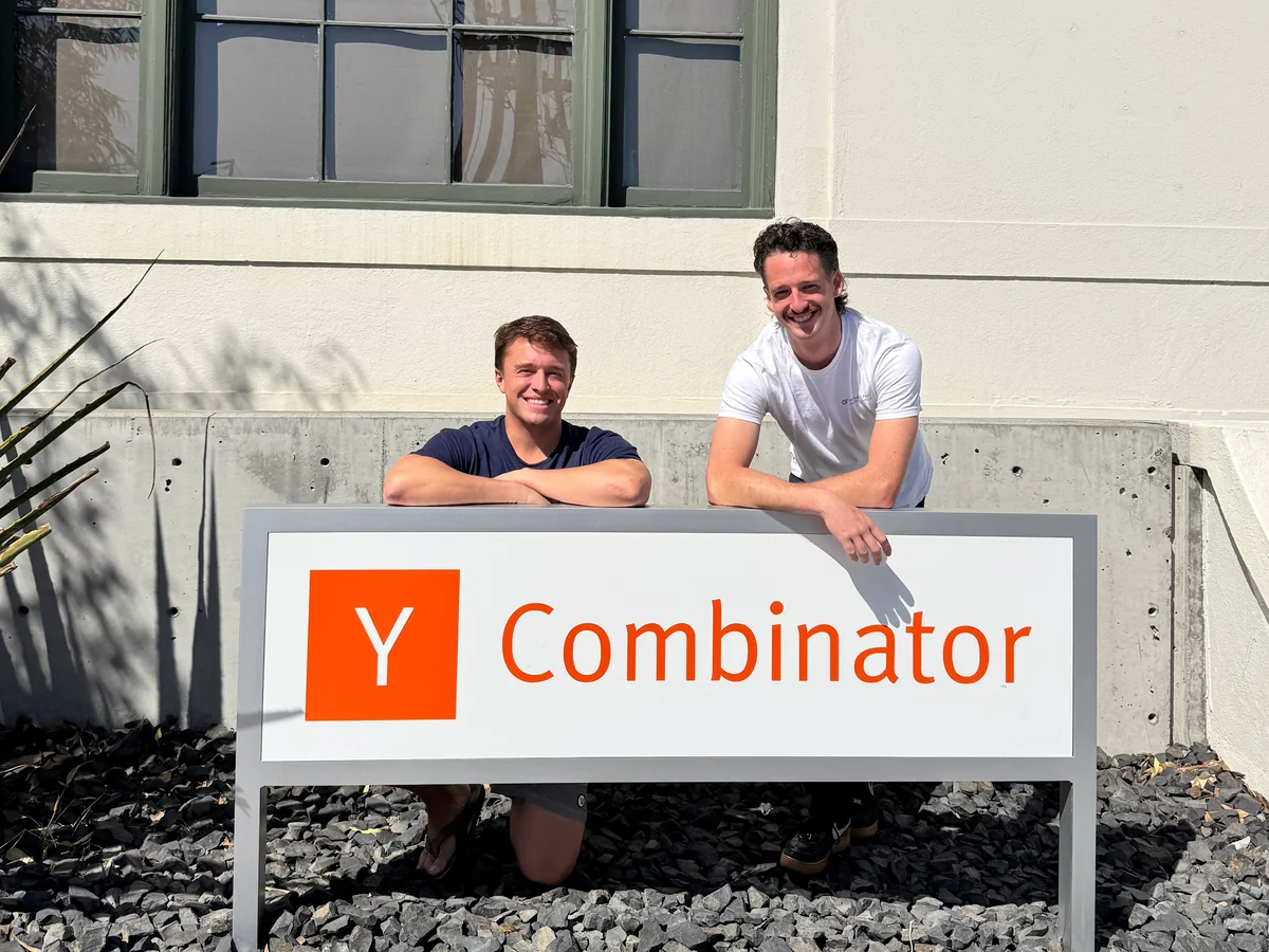 Two teammates behind the Y Combinator sign